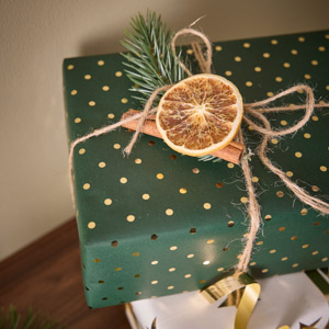 verpacktes Weihnachtsgeschenk mit Orangenscheiben, Tannenzweigen und Naturband