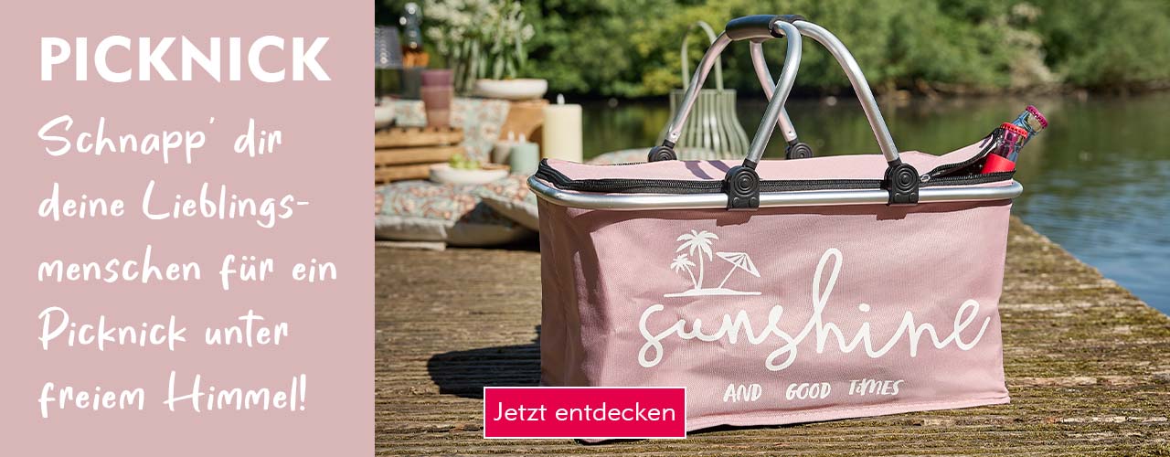 Entdecke Picknick-Zubehör bei Nanu-Nana Ein rosafarbener Picknickkorb auf einem Holzsteg bei Sonnenschein verlinkt auf die Kategorie Picknick